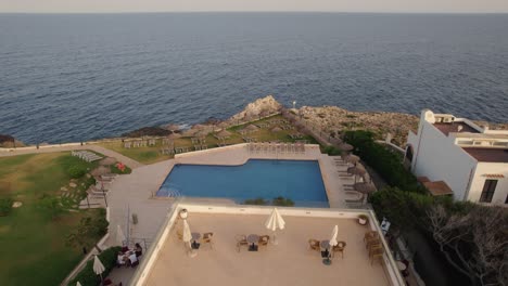 Aerial-view-flyover-Mallorca-holiday-resort-sun-lounger-terrace-overlooking-clear-blue-pool