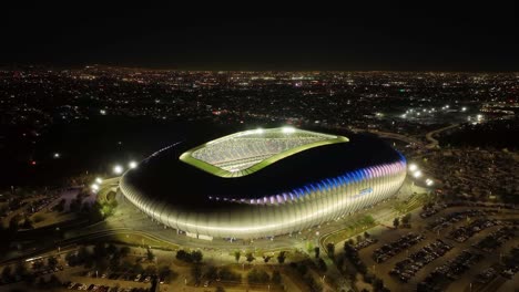 Aerial-view-rising-away-from-the-Estadio-BBVA-stadium,-night-in-Monterrey,-Mexico---pull-back,-drone-shot