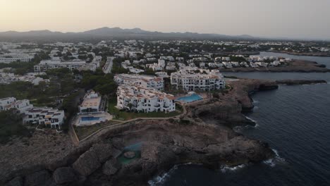 Establishing-aerial-view-rising-over-Mallorca-holiday-resort-hotel-overlooking-Mediterranean-sea-coastal-cliff-edge