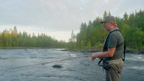 Fliegenfischer-Fischt-In-Einem-Fluss-Mit-Stromschnellen-Im-Hintergrund-Und-Wirft-In-Einer-Sommernacht-Mit-Seiner-Fliegenrute