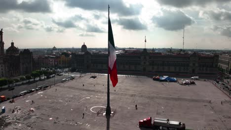 Aerial-view-around-a-large-Mexican-flag-at-the-Zocalo-Square,-in-Mexico-city