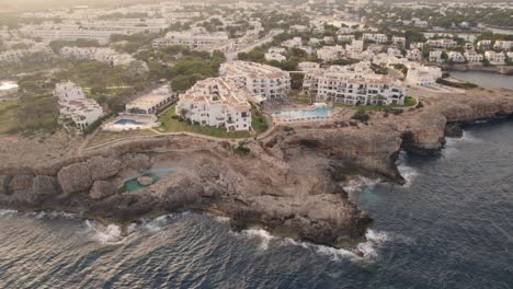 Cinematic-drone-flight-at-sunset-with-luxury-real-estate-on-clifftop-in-Mallorca,-Spain