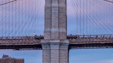 Timelapse-of-people-walking-past-a-pylon-on-the-Brooklyn-Bridge-late-afternoon-with-a-cloudy-sky