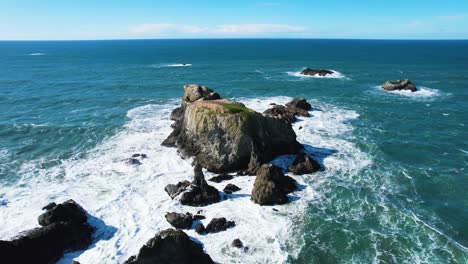 Wunderschöne-4K-Luftdrohnenaufnahme-Von-Meereswellen,-Die-In-Bandon,-Oregon,-Gegen-Felsen-Krachen,-Mit-Mohnblauem-Himmel-Im-Hintergrund