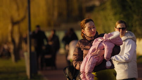 Caucasian-mother-with-her-baby-in-arms-to-soothe-her-in-the-park-with-sunset-light