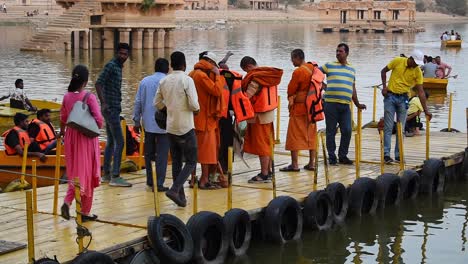 Few-Indian-monks-wearing-life-jacket-before-stepping-in-the-boat-at-gadisar-lake,-tourist-monk-wearing-life-jacket