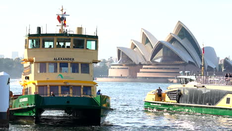 Passengers-embark-a-Sydney-ferry-in-front-of-the-Sydney-opera-house,-Australia