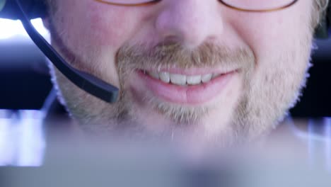 Face-close-up:-Smiling-bearded-man-with-telephone-headset-nods,-talks