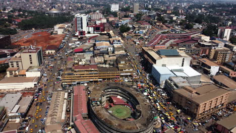 Aerial-view-over-the-city-of-Yaounde,-revealing-the-old-Central-Market-,-in-sunny-Cameroon---reverse,-tilt,-drone-shot