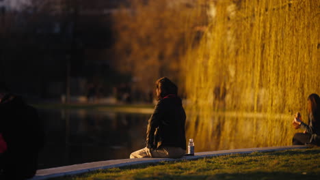 Slow-motion-shot-of-a-man-sitting-relaxing-at-the-side-of-the-lake-enjoying-the-views