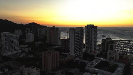 Luftaufnahme-Des-Silhouette-Hotels-An-Der-Küste-Von-Santa-Marta,-Abenddämmerung-In-Kolumbien---Aufsteigend,-Drohnenaufnahme