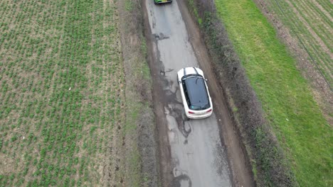 Cars-maneuvering-around-large-potholes-on-country-lane-UK-overhead-birds-eye-view