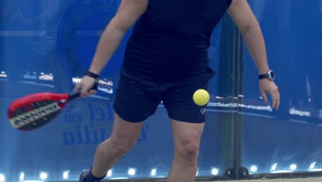 Close-up-of-mature-semi-bold-man-serving-slow-motion-inside-indoor-padel-court