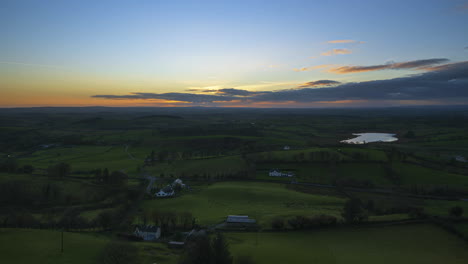 Time-lapse-of-rural-farming-landscape-of-distant-lake-in-grass-fields-and-hills-during-dramatic-cloudy-sunset-viewed-from-Keash-caves-in-county-Sligo-in-Ireland