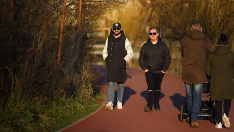 Two-young-friends-wearing-sunglasses-strolling-leisurely-in-the-park