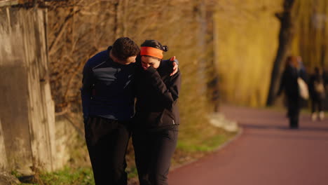 Young-couple-walking-and-laughing-after-a-run,-in-a-public-city-park,-on-a-spring-evening