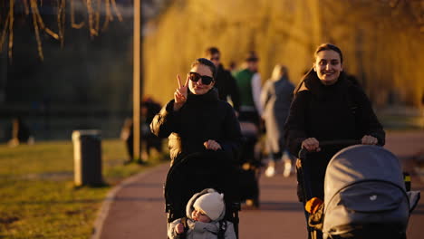 Slow-motion-shot-of-mothers-pushing-prams-in-a-park-and-having-a-laugh