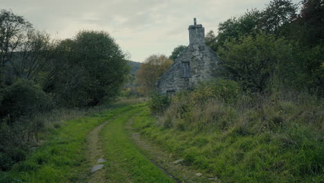 old-stone-house-next-to-a-wooded-pathway