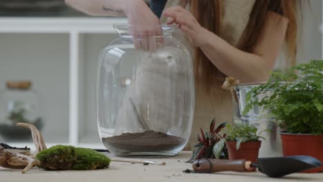 A-young-woman-cleans-a-glass-jar-in-which-she-creates-a-tiny-live-forest-ecosystem---close-up