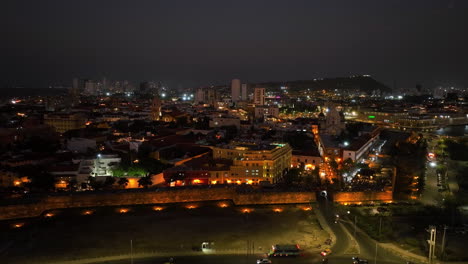 Vista-Aérea-Frente-Al-Distrito-Centro-Iluminado,-Noche-En-Cartagena,-Colombia---Seguimiento,-Disparo-De-Drones