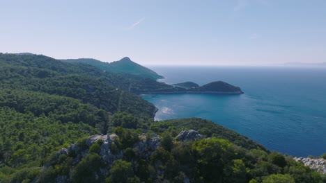 Aerial-arc-shot-gently-flying-around-the-coastline-of-Lastovo-Island,-Croatia-on-a-bright-morning