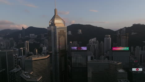 Toma-Aérea-Del-Edificio-De-La-Plaza-Central-De-Lujo-En-Wan-Chai-Durante-La-Puesta-De-Sol-Con-La-Silueta-De-La-Cresta-De-La-Montaña-En-El-Fondo---Ciudad-De-Hong-Kong,-China