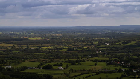 Time-lapse-of-blurry-grass-in-foreground-and-rural-farmland-in-distance-during-a-cloudy-sunny-day-viewed-from-above-Lough-Meelagh-in-county-Roscommon-in-Ireland