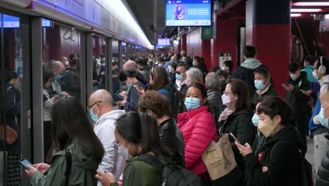 Pendler-Mit-Gesichtsmasken-Warten-Geduldig-Darauf,-Dass-Ein-U-Bahn-Zug-An-Einer-überfüllten-MTR-U-Bahn-Station-In-Hongkong-Ankommt