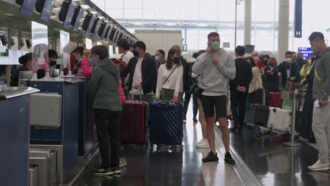 Flugpassagiere-Stehen-Am-Schalter-Einer-Fluggesellschaft-Im-Internationalen-Flughafen-Hongkong-Schlange-Und-Checken-Ein
