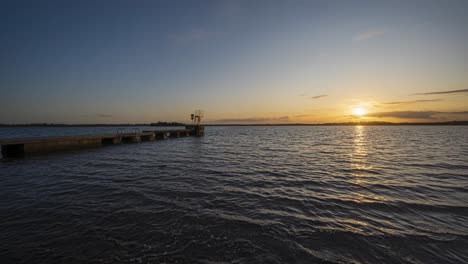 Panorama-Bewegungszeitraffer-Eines-örtlichen-Sees-Mit-Wenigen-Menschen-Auf-Einem-Betonsteg-In-Der-Grafschaft-Westmeath-In-Irland-Bei-Sonnenuntergang-Mit-Wolken-über-Dem-Horizont