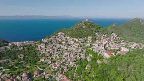 Arcing-flyover-shot-gently-circling-around-the-town-of-Lastovo,-Croatia-on-a-bright-clear-day