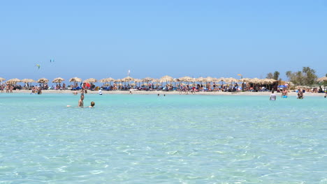 Beach-packed-with-umbrellas-and-tourist-in-waters-of-Elafonissi-beach,-Crete
