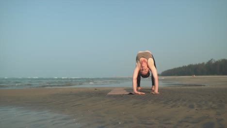 Kontrollierte-Yoga-Posen,-Die-Flexibilität-Am-Strand-Demonstrieren
