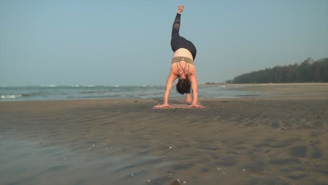 Women-doing-three-legged-yoga-position-on-beach-while-on-holiday