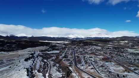 Cloudy-day-flyover-of-Fairplay,-Colorado-on-a-winter-day-with-blue-skies