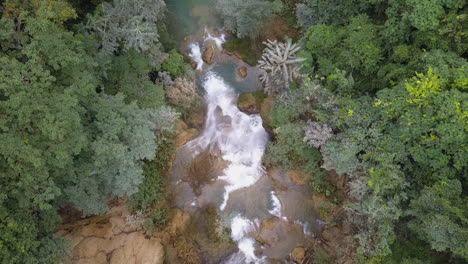 Descending-overhead-view-of-waterfall-flowing-in-rural-tropical-jungle