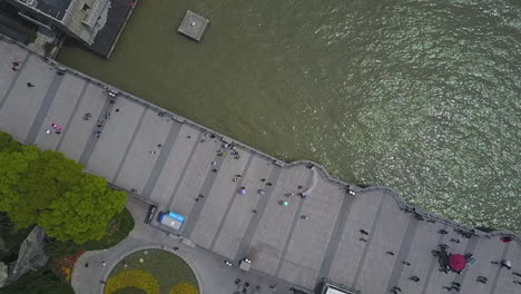 Die-Luftaufnahme-Von-Oben-Senkt-Sich-Zu-Den-Menschen,-Die-Am-Ufer-Des-Shanghai-Flusses-Spazieren-Gehen