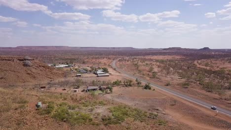 Aerial-Shot-of-a-Rest-Stop-in-the-Outback-alongside-Stuart-Highway-under-a-Patchy-Sky,-Australia