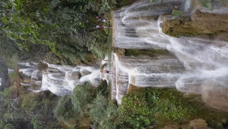 Vertical-format:-Aerial-flies-through-jungle-to-Kuang-Si-Falls-in-Laos