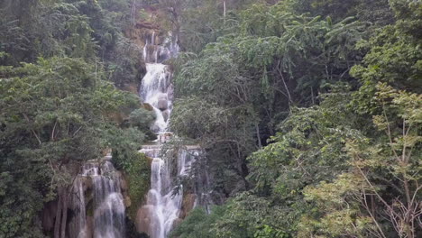 Misty-jungle-aerial-retreats-from-beautiful-popular-Kuang-Si-Waterfall