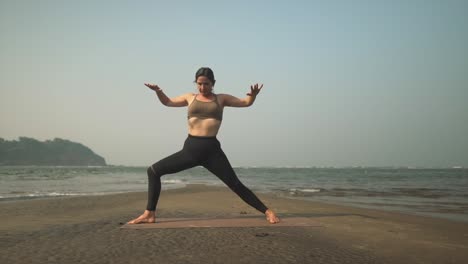 Warrior-2-yoga-pose-being-completed-in-slow-mo-by-teacher-on-coastline