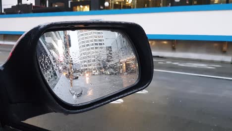 Tráfico-Del-Centro-De-La-Ciudad-En-La-Ciudad-Capital-De-Wellington-En-Nueva-Zelanda-Aotearoa,-Luces-De-Vehículos-Y-Gotas-De-Lluvia-En-La-Vista-Del-Espejo-Del-Ala-Del-Automóvil