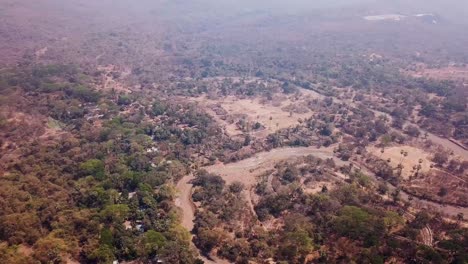 Aerial-Shot-of-a-River-Slithering-through-an-Arid-Forest-in-Sanjay-Gandhi-National-Park,-India