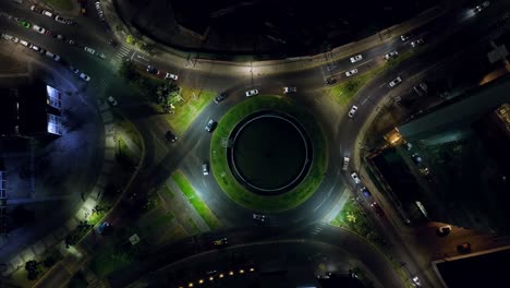 Top-down-nighttime-shot-of-cars-driving-through-a-roundabout-in-Iquique,-Chile