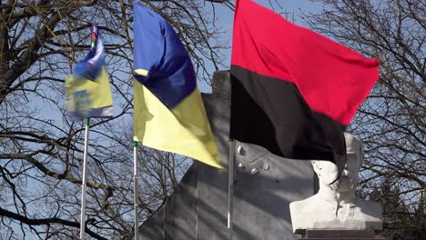 The-regional-flag-of-Kherson,-the-national-Ukraine-flag-and-the-red-and-black-flag-of-Ukrainian-resistance-fly-next-to-a-statue-of-Taras-Hryhorovych-Shevchenko