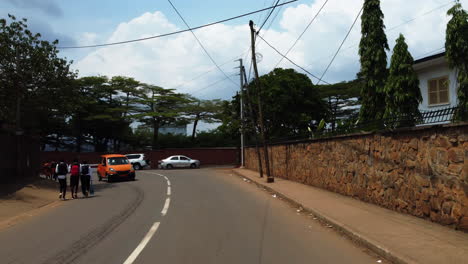 Driving-in-the-suburbs-of-Yaounde-city,-sunny-day-in-Cameroon,-Africa---POV-shot
