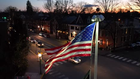 Bandera-Estadounidense-Ondeando-En-La-Histórica-Plaza-De-La-Ciudad-Por-La-Noche