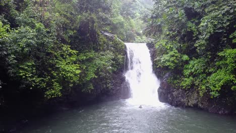 Indonesian-boy-jumps-off-jungle-waterfall-cliff-into-deep-pool-below
