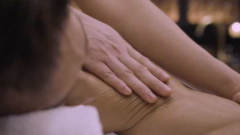 Mann-Genießt-Massage,-Schöne-Weibliche-Hände-Massieren-Gesundheitspflege-Sanft-Berührende-Ölmassage,-Männliche-Tiefenentspannung-Wellness-Spa-Erlebnis,-Traditionelle-Thai-Massage-Therapie