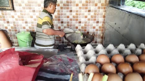 Chef-Indonesio-Cocinando-Verduras-Salteadas-En-Bali-Cap-Cay-Local-Tienda-Warung-Un-Negocio-Familiar-Marido-Y-Mujer-Entre-Ofrendas-Religiosas-Hindúes